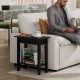 Narrow black wood end table with storage shelf, perfect for small spaces, beside a sofa in a modern living room.